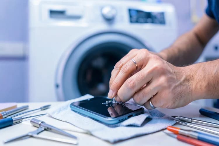 Um técnico de celular montando um smartphone com ferramentas em sua bancada.