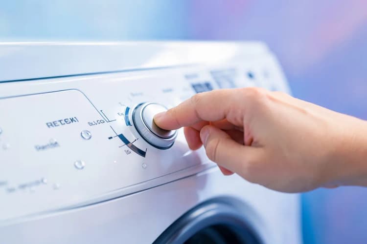 Mão pressionando o botão de reset em um painel de controle de máquina de lavar.