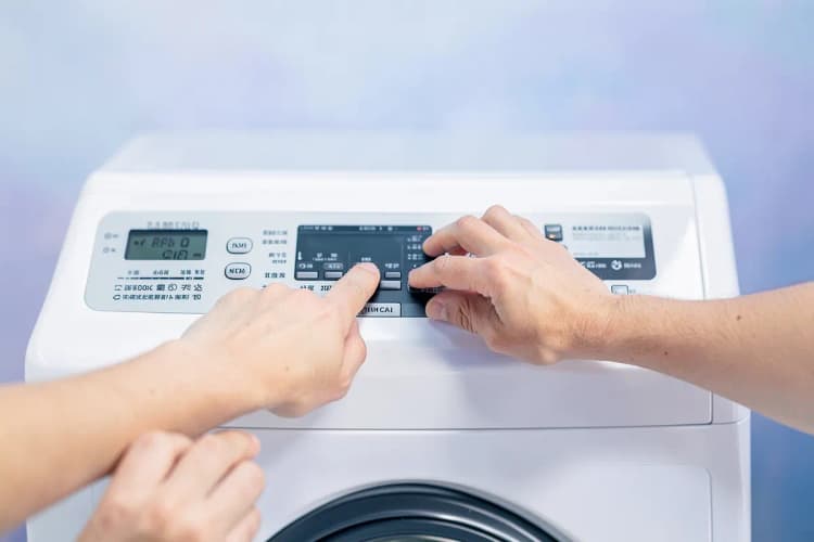 Mãos apertando botões no painel de controle de uma lava e seca Samsung.