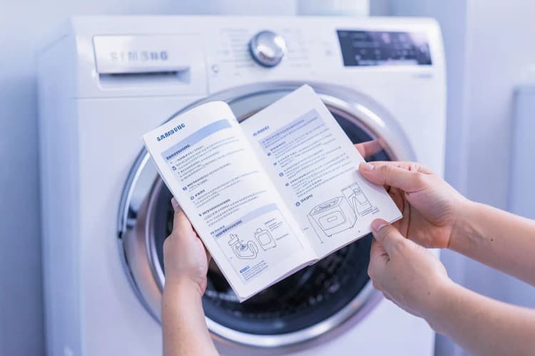 Uma pessoa lendo o manual de instruções de uma máquina lava e seca Samsung.