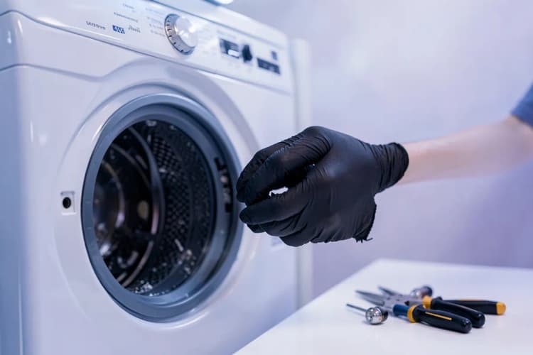 Pessoa realizando manutenção em uma máquina de lavar e secar Samsung, focando em componentes internos.