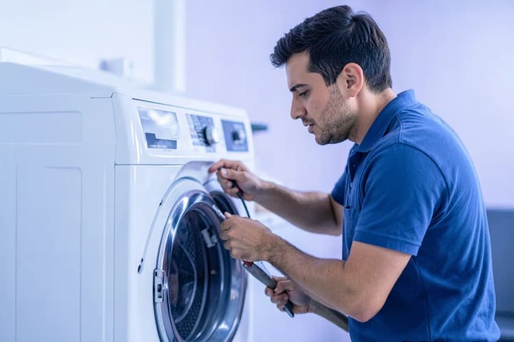Técnico de eletrodomésticos trabalhando em uma máquina de lavar e secar.