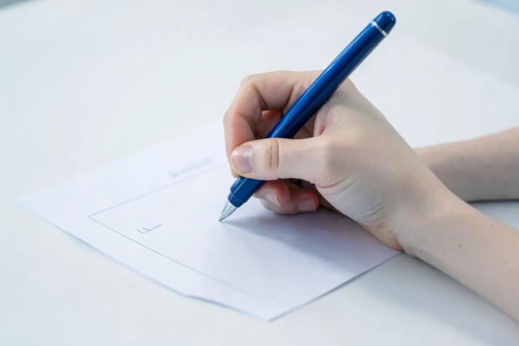 Mão preenchendo um formulário de solicitação de serviço em uma mesa.