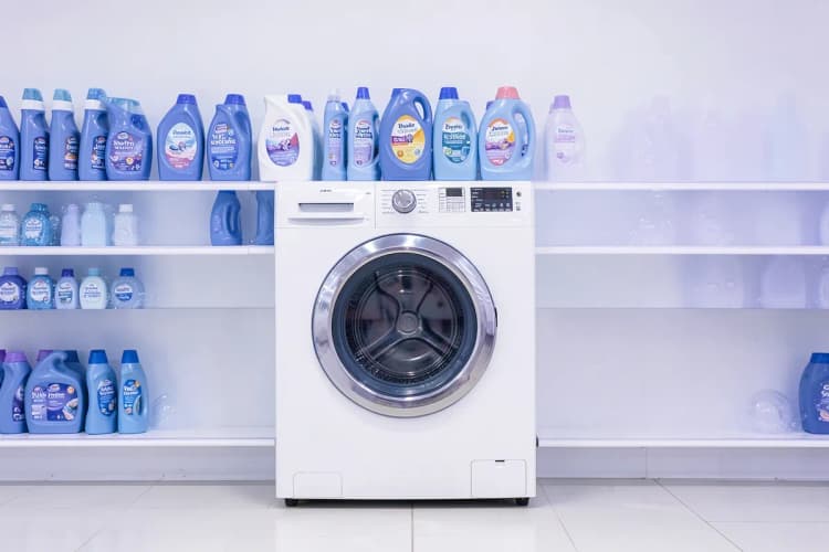 Uma prateleira com produtos de limpeza para máquinas de lavar, como sabão em pó e amaciante.